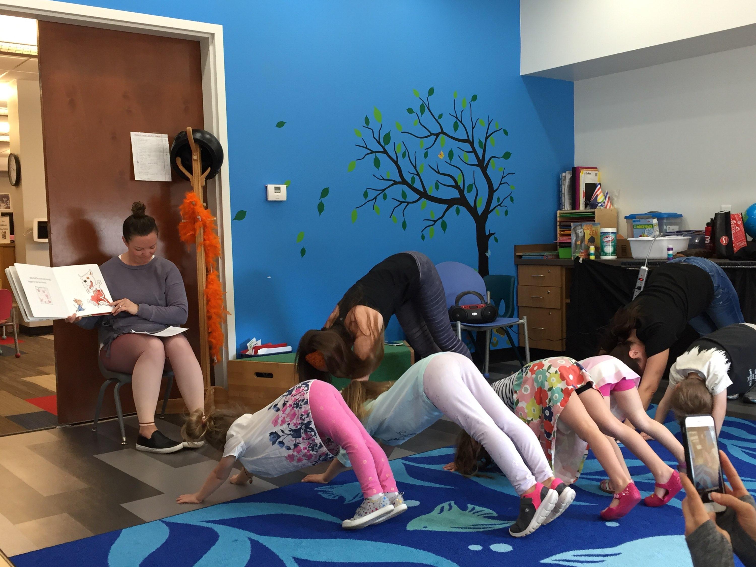 several kids do downward dog yoga pose during storytime