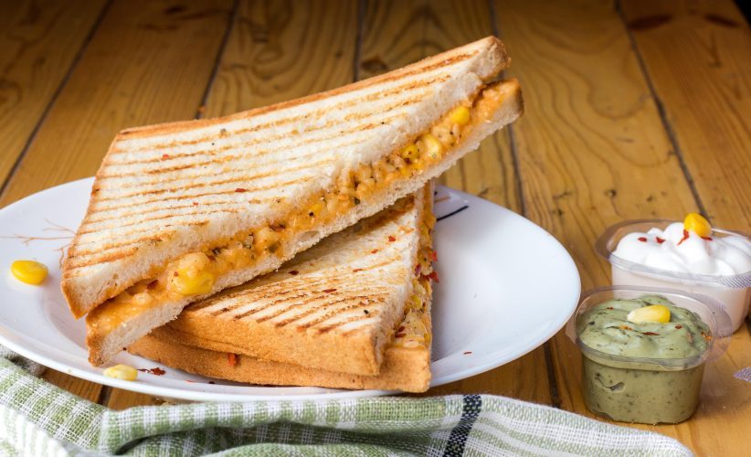 a grilled cheese sandwich sits on a white plate on a wooden table